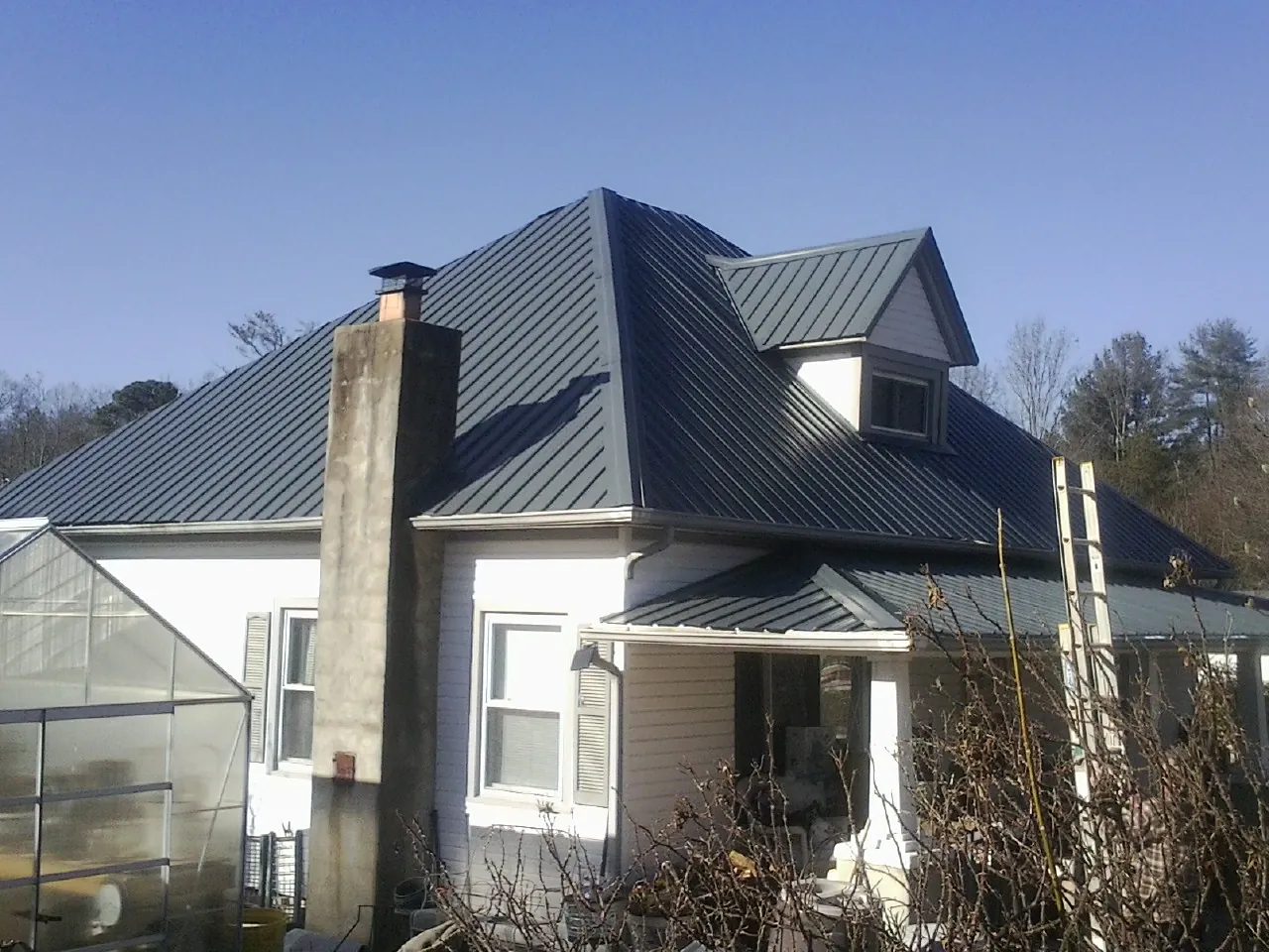 Dark blue standing seam metal roof on a white farmhouse with dormer in Scottsdale
