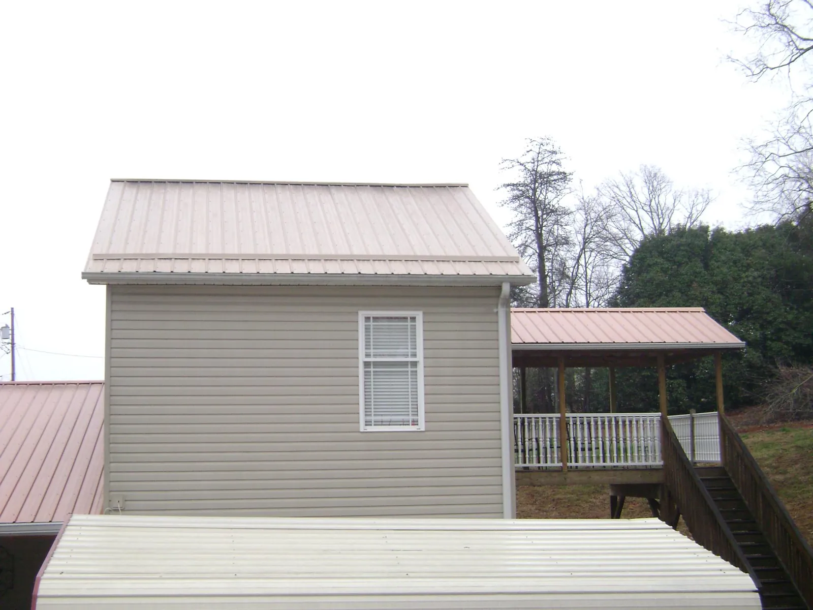 Tan metal roofs on a two story addition and attached porch, from a Roof Replacement job in Scottsdale