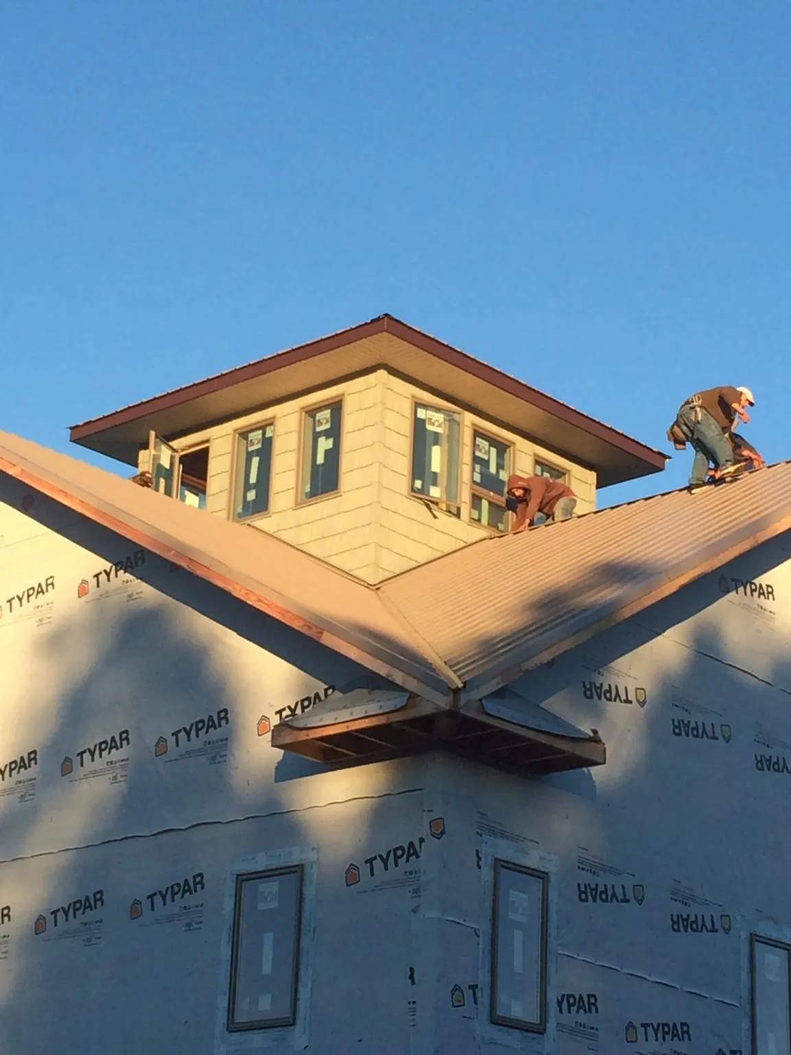 Roofers working around a rooftop cupola on a new metal roof at sunset — Roof Waterproofing in Scottsdale by Roofing Brothers